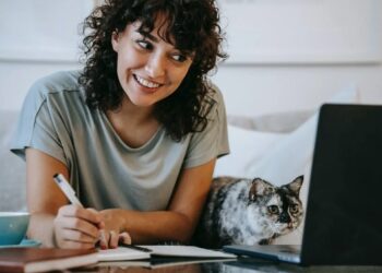 Mujer estudiando con portatil y gato acompañandola