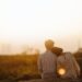 Pareja abrazandose sentados frente a puesta de sol